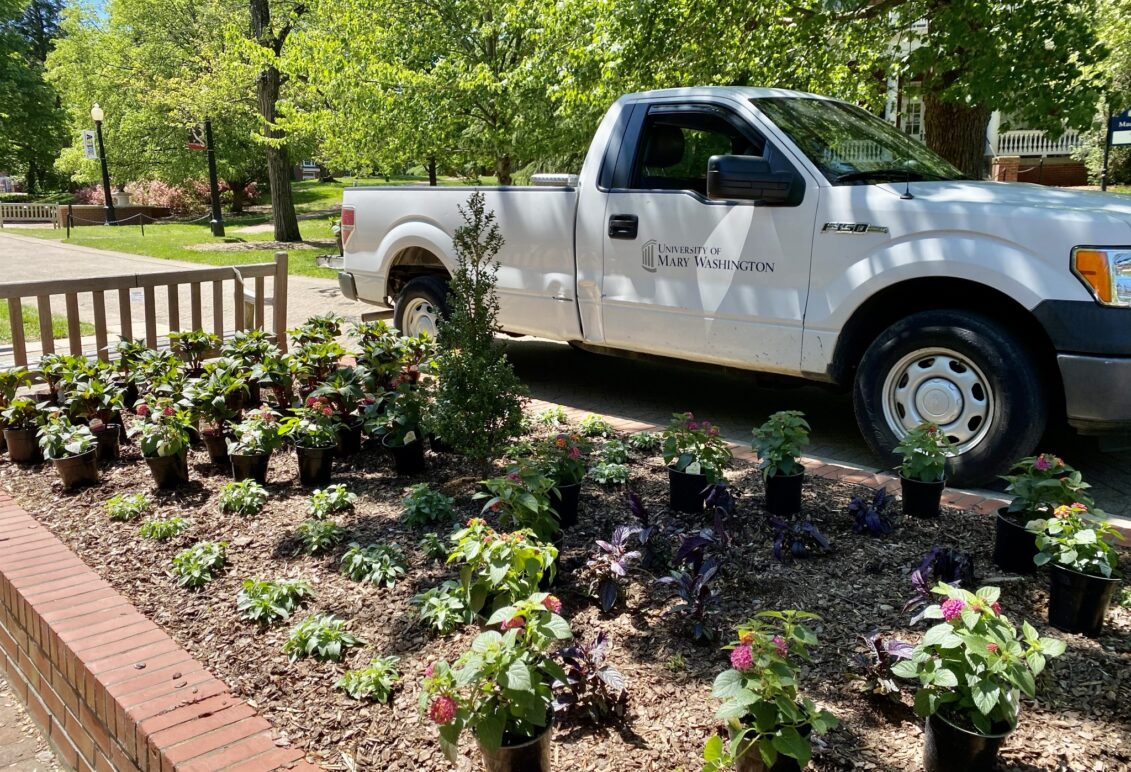 Facilities truck on campus walk next to flower beds